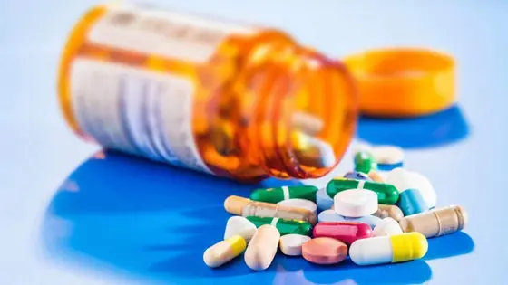 Assorted tablets and capsules spilling from a bottle